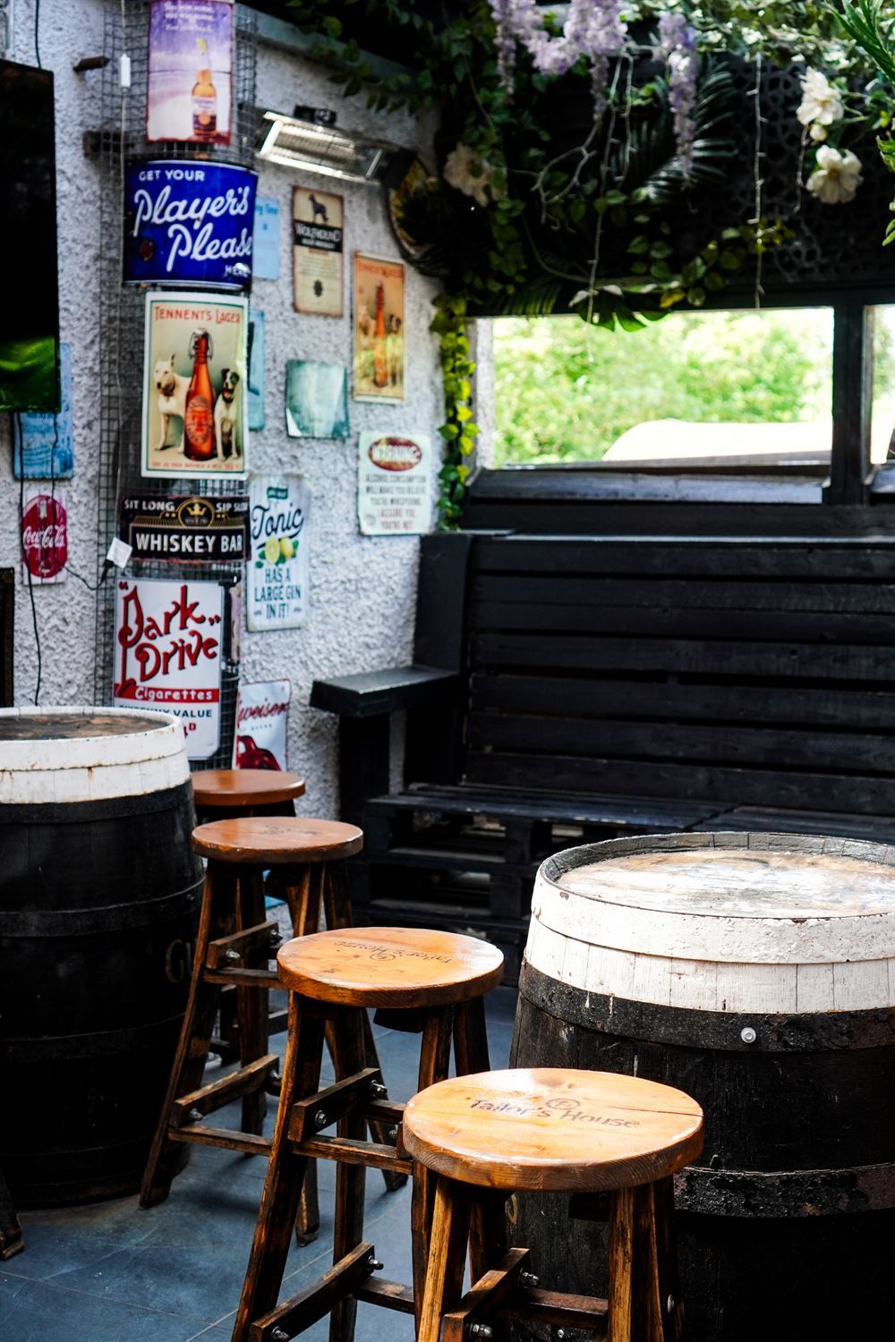 The Tailor's House beer garden with whiskey-barrel tables and vintage signage
