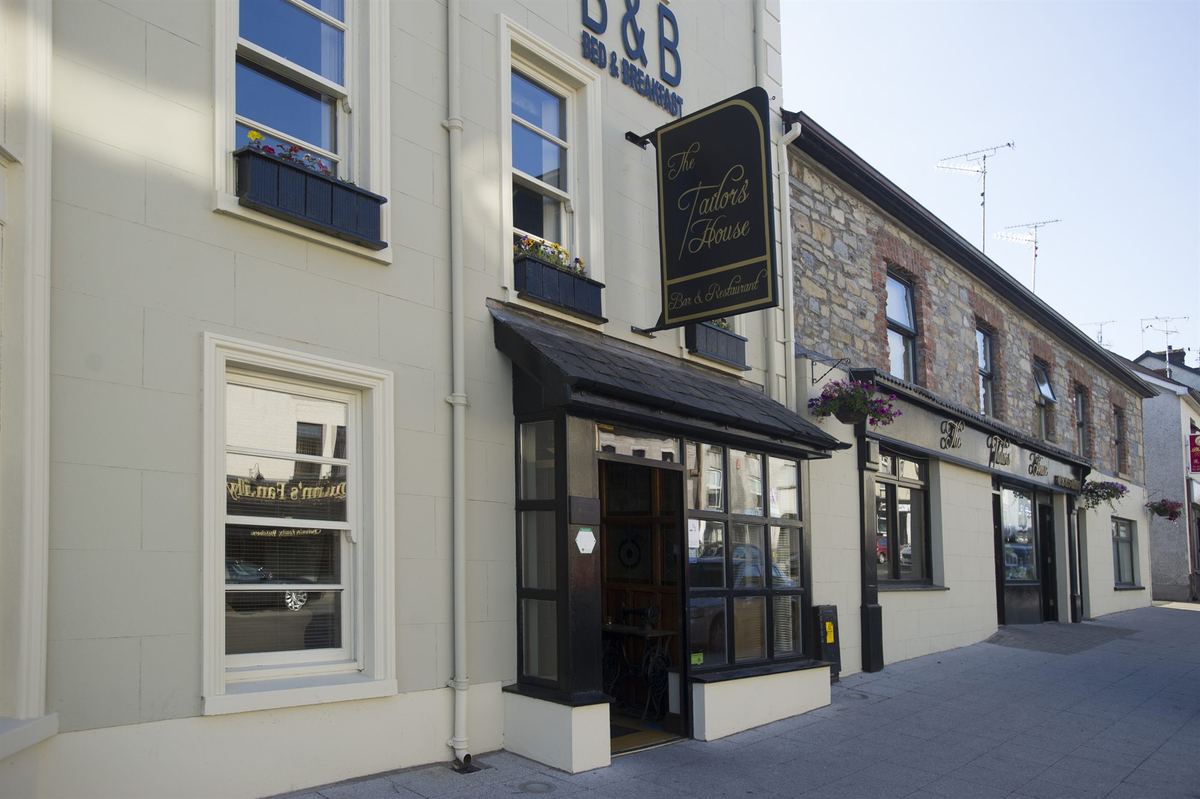The angled front exterior of The Tailor's House showing the hanging sign and entrance canopy on Main Street, Ballygawley