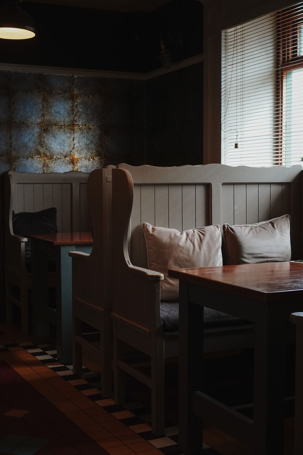 Cosy restaurant snug with painted settle benches and a tiled floor at The Tailor's House