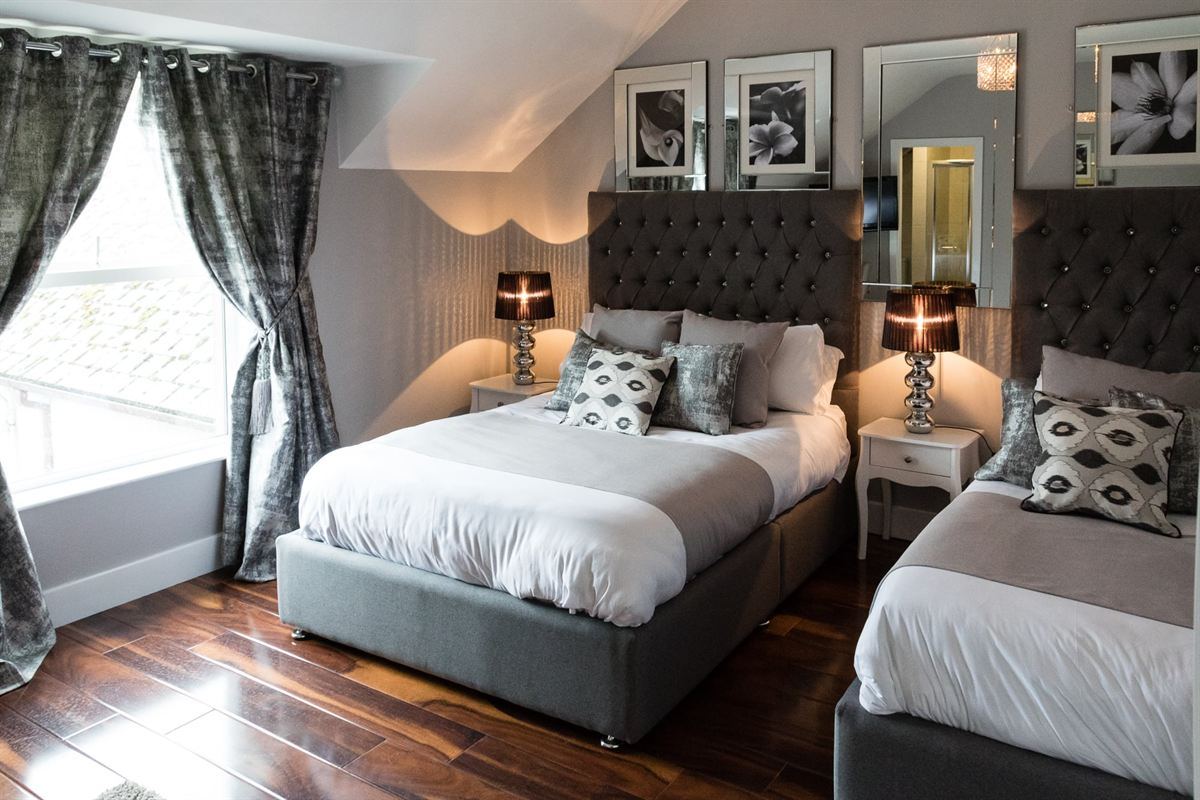 Family guest room with double and single beds beside a bright window