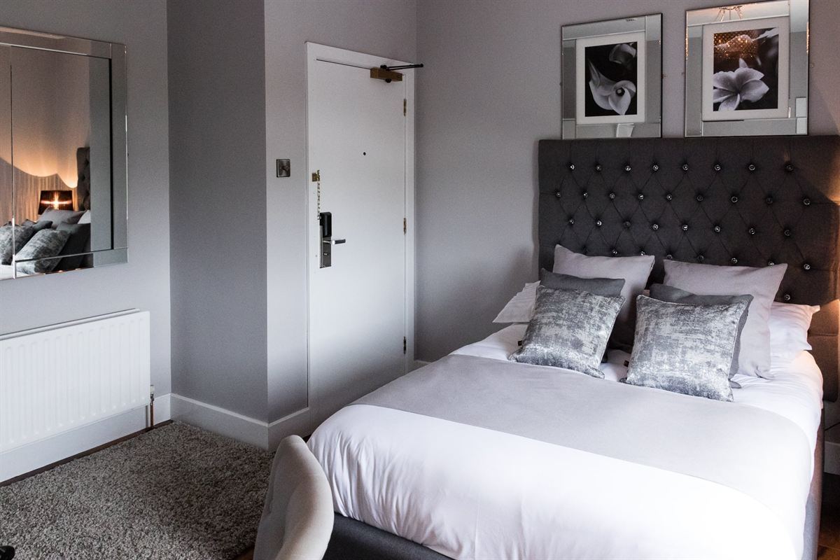 Double guest room with a tufted headboard and crushed-velvet cushions